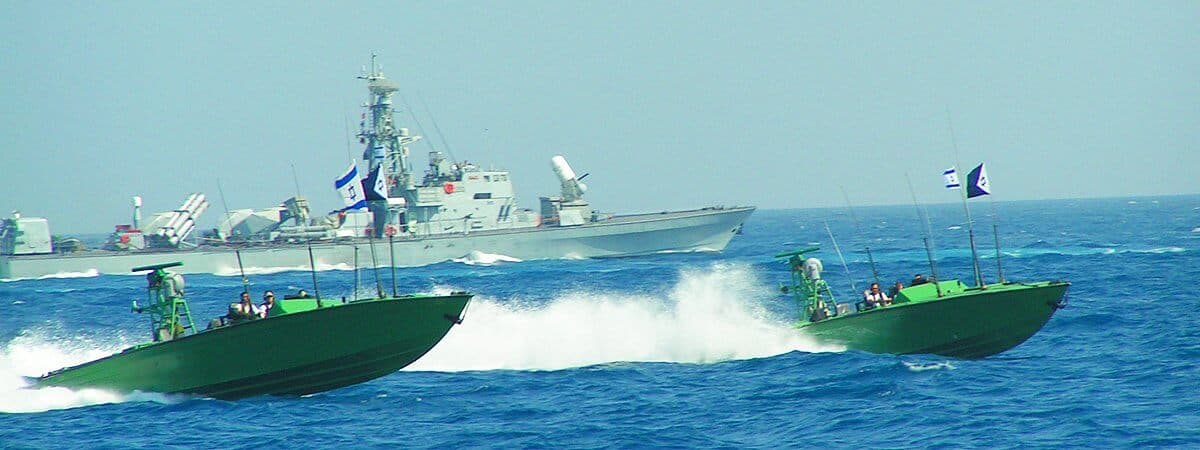 Fast green patrol boats maneuvering at speed in front of an Israeli Navy missile ship